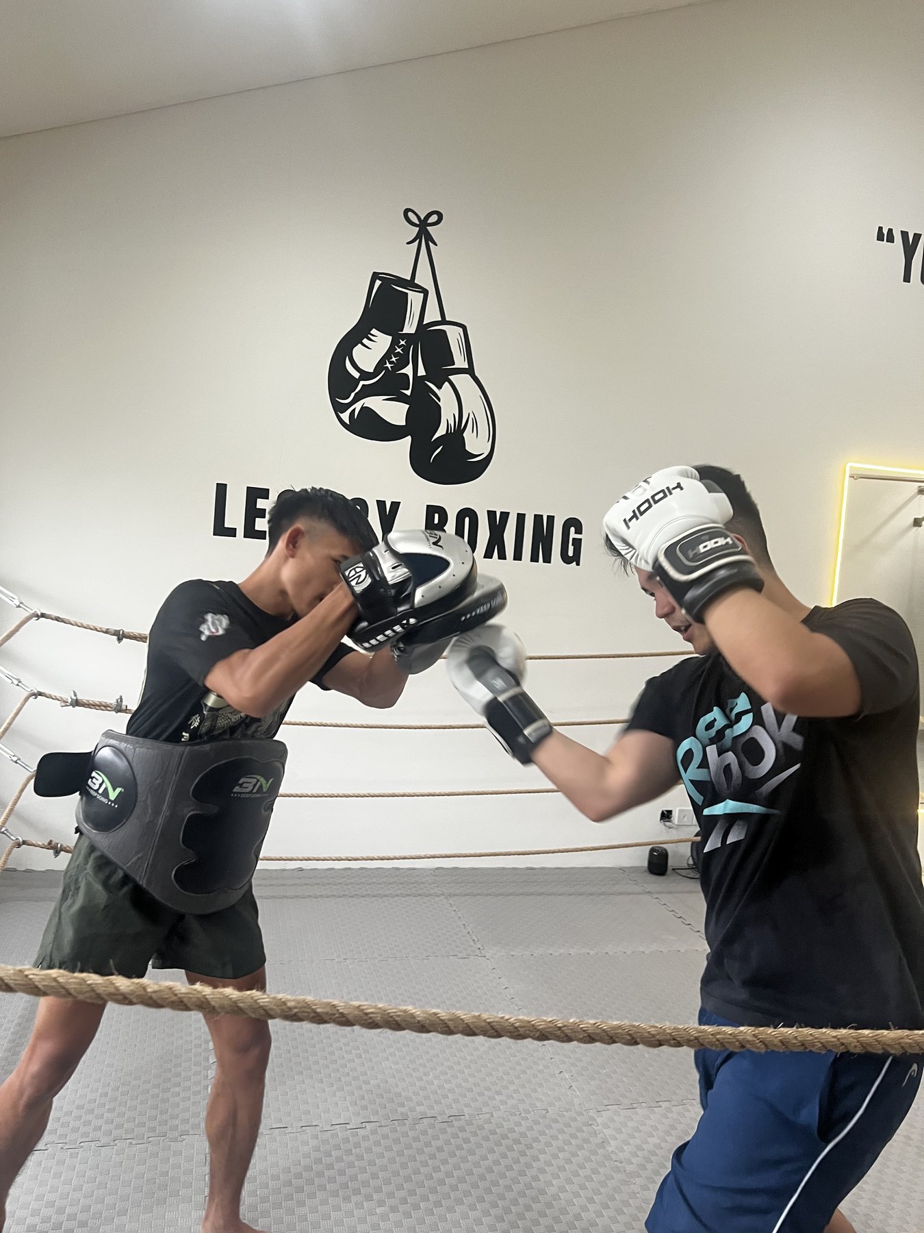 Trainer holding pads for a student at Legacy Boxing Camp